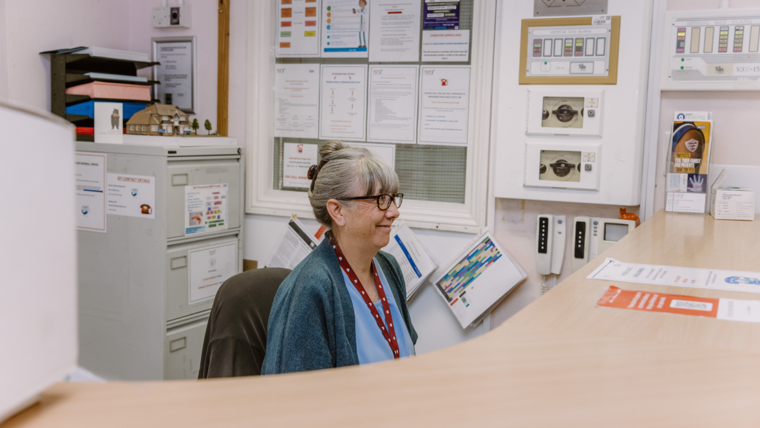 Hospital receptionist sitting behind a reception desk.
