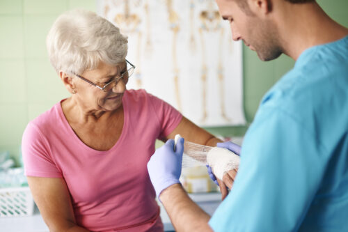 Healthcare professional applying a bandage to an older person’s arm.